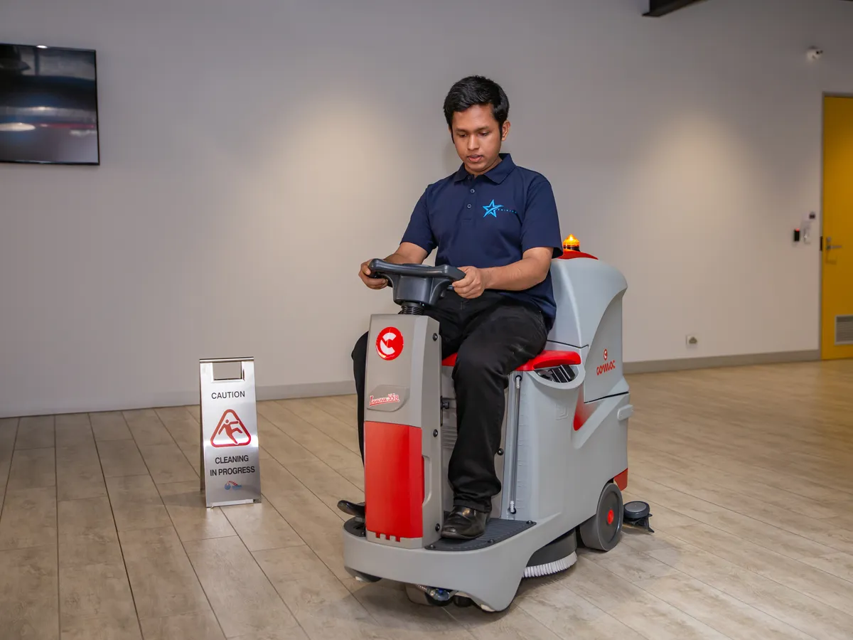 A Star Shining operator on a ride-on scrubber in an office